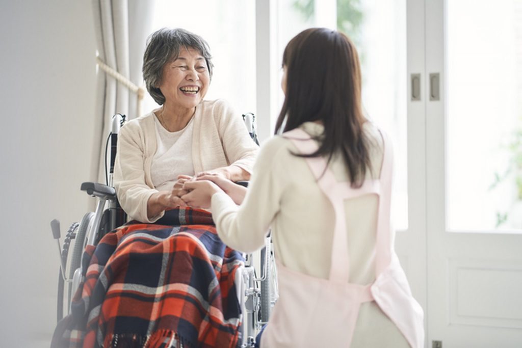 介護士の女性が車椅子に乗る高齢女性と会話している様子